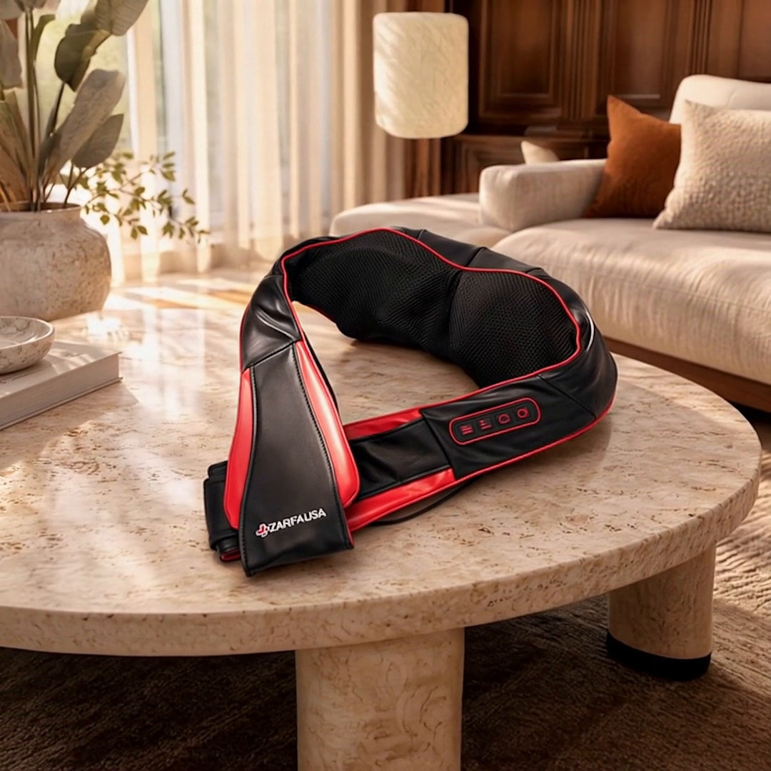 Zarifa Neck & Shoulder Massager in black with red trim, showing the controls and use in a warm, elegant living room.