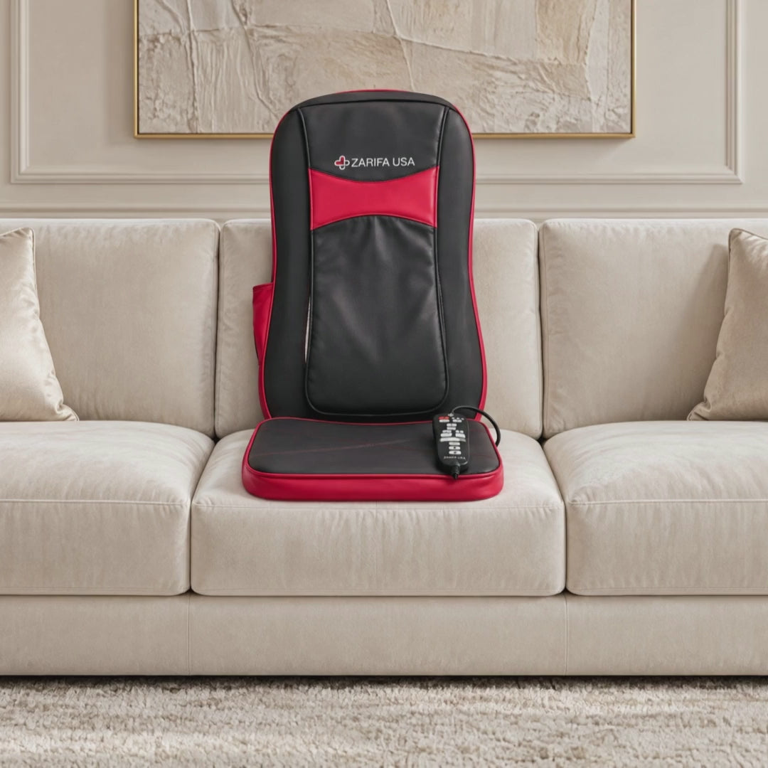 Black and red Zarifa Classic Cushion supported on an ivory sofa with its wired controller on the seat pad