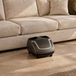 Compact Zarifa Z-Smart Foot Massager in front of an ivory sofa in a warm luxury living room, with close-ups of the five controls and silver trim.